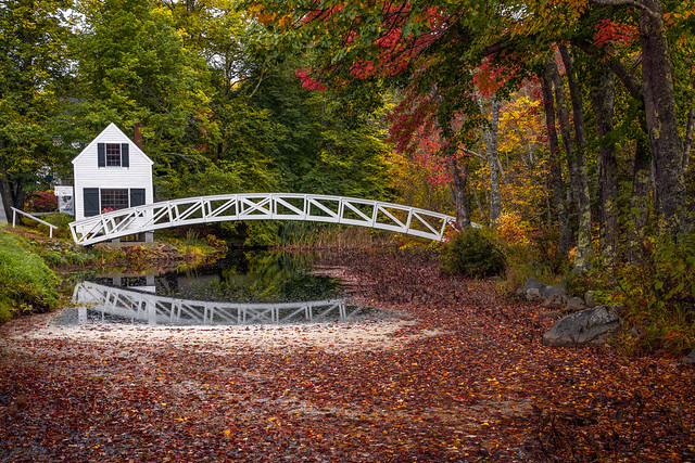 White arched Somesville Bridge reflected in still water among fall foliage